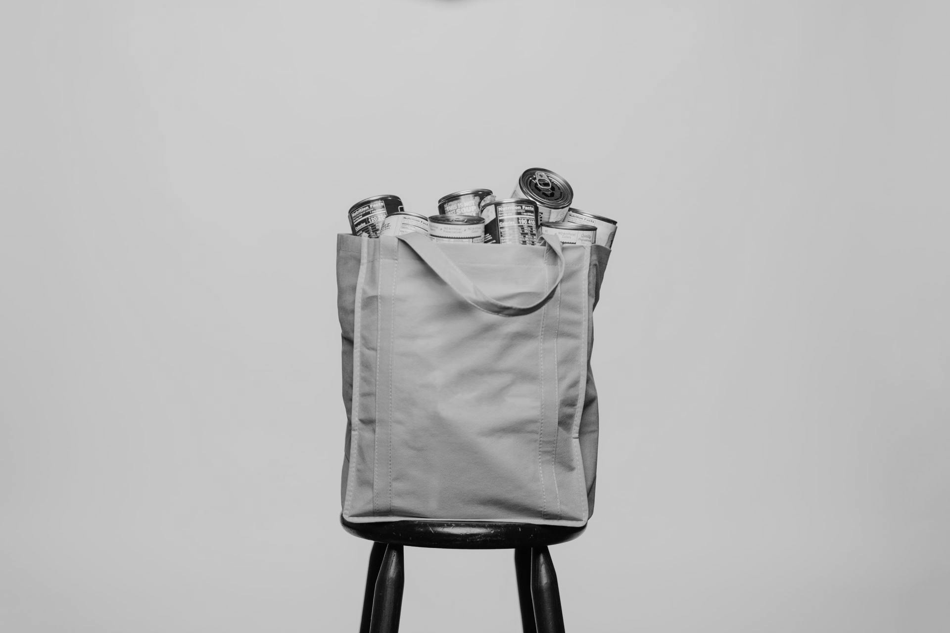 Gray tote bag on a black stool against a plain light background